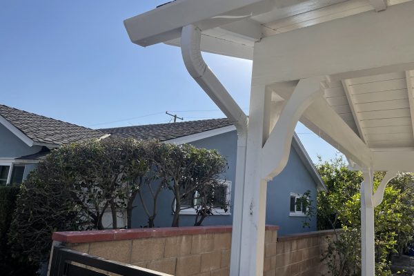 A closeup of white gutters off of the side of an overhang.