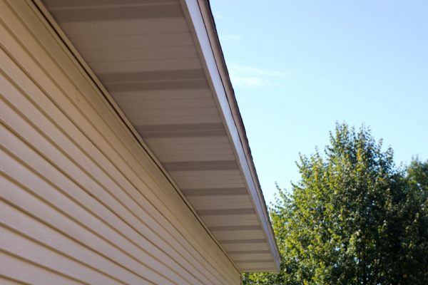 A close up image of aluminum siding and fascia on a yellow house.
